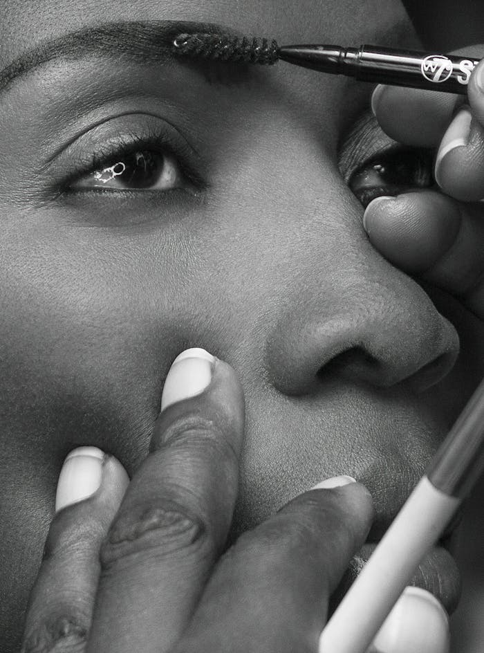 Detailed view of brushes applying makeup on eyes, focused on precision.