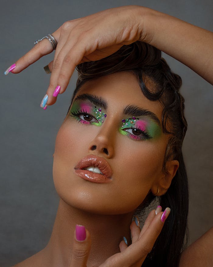 pexels-photo-13304806 Close-up portrait showcasing vibrant makeup and colorful eyeshadow, featuring manicured nails.